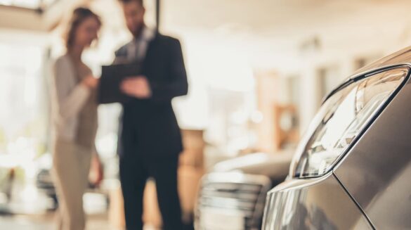 Frau und Mann mit Klemmbrett im Autohaus